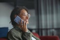 A business woman with glasses sitting on a couch talking on a cell phone in nice modern coworking office Royalty Free Stock Photo