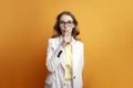 business woman in glasses and suit is silent and covers her mouth with finger on colored background Royalty Free Stock Photo