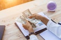 Business woman gripping The United States hundred-dollar bills in her hand and some put on the table full with business charts and Royalty Free Stock Photo