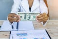 Business woman gripping The United States hundred-dollar bills in her hand and some put on the table full with business charts and Royalty Free Stock Photo