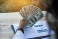 Business woman gripping The United States hundred-dollar bills in her hand and some put on the table full with business charts and Royalty Free Stock Photo