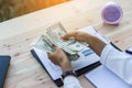 Business woman gripping The United States hundred-dollar bills in her hand and some put on the table full with business charts and Royalty Free Stock Photo