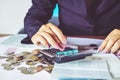 business woman hand calculating her monthly expenses during tax season with coins, calculator, Royalty Free Stock Photo