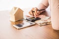 Woman hand counting money paper currency with smart phone,house model and calculator on desk, planing to buy or rent home Royalty Free Stock Photo