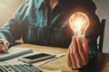 business woman hand holding light bulb in office. conept saving Royalty Free Stock Photo