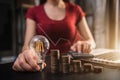 Business woman hand holding lightbulb with coins stack on desk. Royalty Free Stock Photo