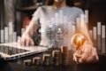 Business woman hand holding lightbulb with coins stack on desk. Royalty Free Stock Photo