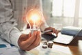 business woman hand holding lightbulb with coins stack on desk. concept saving energy power Royalty Free Stock Photo