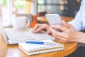 Business woman hand holding a mobile phone and working on a laptop in an office. Royalty Free Stock Photo