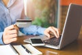 Business woman hand holds a credit card and uses a laptop computer to shop online.