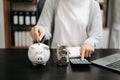 Business woman hand putting money coin into piggy bank with step of growing stack coins for saving money at modern office Royalty Free Stock Photo