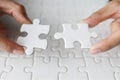 Business woman hand is trying to connect couple White jigsaw puzzle piece on a blue background. Symbol of association and Royalty Free Stock Photo