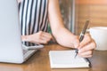 Business woman hand working at a computer and writing on a noteped with a pen in the office. Royalty Free Stock Photo