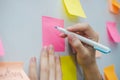 Business woman hand writing with colored sheets sticky note paper on white board background