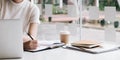 Business woman hand writing on notebook, work on laptop computer with calculator on the desk at modern home office. Online working Royalty Free Stock Photo