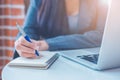 Business woman hand is writing on a notepad with a pen and have a laptop computer on the desk in the office Royalty Free Stock Photo