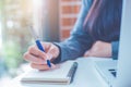 Business woman hand is writing on a notepad with a pen and have a laptop computer on the desk in the office Royalty Free Stock Photo