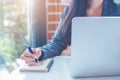 Business woman hand is writing on a notepad with a pen and have a laptop computer on the desk in the office Royalty Free Stock Photo