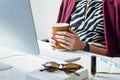 Business woman having cup of coffee at desk in minimalistic office. Young female person in front of desktop computer at modern Royalty Free Stock Photo