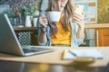 Business woman having a facetime video call. Happy and smiling girl working from home office kithcen and drinking coffee Royalty Free Stock Photo