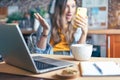 Business woman having a facetime video call. Surprised girl working from home office kithcen and drinking coffee. Using computer Royalty Free Stock Photo