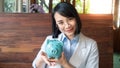 A business woman is holding  a blue piggy bank  close to her face, saving money is an investment for the future. Banking Royalty Free Stock Photo