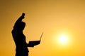 Business woman holding laptop at sunset silhouette. Royalty Free Stock Photo