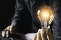 Business woman holding light bulb on the desk in office and using computer in financial,accounting,energy,idea concept Royalty Free Stock Photo