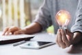 Business woman holding light bulb on the desk in office and using  computer in  financial,accounting,energy,idea concept Royalty Free Stock Photo