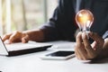 Business woman holding light bulb on the desk in office and using  computer in  financial,accounting,energy,idea concept Royalty Free Stock Photo