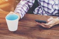 Business woman holding phone and coffee cup on wooden table. Vintage toned. Royalty Free Stock Photo