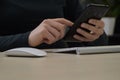 Business woman  holding the smart mobile phone in her hands - close up.  Keyboard and wireless mouse next to her hands Royalty Free Stock Photo