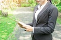 Business woman holding tablet computer with garden background.