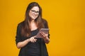 Business woman holding tablet computer isolated against yellow background Royalty Free Stock Photo