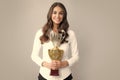 Business woman holding a trophy. Businesswoman concept winner success. Smiling female with trophy isolated on gray Royalty Free Stock Photo