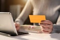 Business woman holds a credit card and transact with a tablet at home.