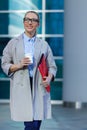 The young business woman holds in her hands folder with documents and cup of coffee. Businesswoman standing next to the business Royalty Free Stock Photo