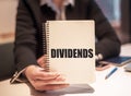 Business woman holds a notebook with the text -dividends. Business concept Royalty Free Stock Photo