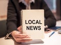 Business woman holds a notebook with the text LOCAL NEWS