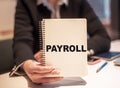 Business woman holds a notebook with the text PAYROLL