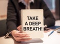 Business woman holds a notebook with the text TAKE A DEEP BREATH Royalty Free Stock Photo