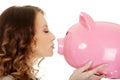 Business woman kissing a piggybank.