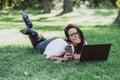 Business woman, lies in a summer grass park, using a laptop with a glass of coffee in hand. Remote work during quarantine. Woman Royalty Free Stock Photo