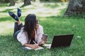 Business woman, lies in a summer grass park, using a laptop with a glass of coffee in hand. Remote work during quarantine. Woman Royalty Free Stock Photo