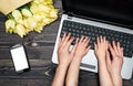 Business woman and little son using laptop computer in office. Woman and baby hands typing on laptop keyboard near mobile phone Royalty Free Stock Photo