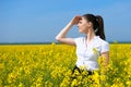 Business woman looking into the distance. Young girl in yellow flower field. Beautiful spring landscape, bright sunny day, rapesee Royalty Free Stock Photo