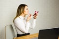 Business woman looking in the mirror and using lipstick at her worlplace Royalty Free Stock Photo