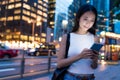 Business woman looking at mobile phone in city at night Royalty Free Stock Photo