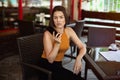 Business woman looking at the phone in a cafe at a table with scattered papers on the table and a cup of coffee Royalty Free Stock Photo