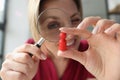 Business woman looking at red wooden figure through magnifying glass.